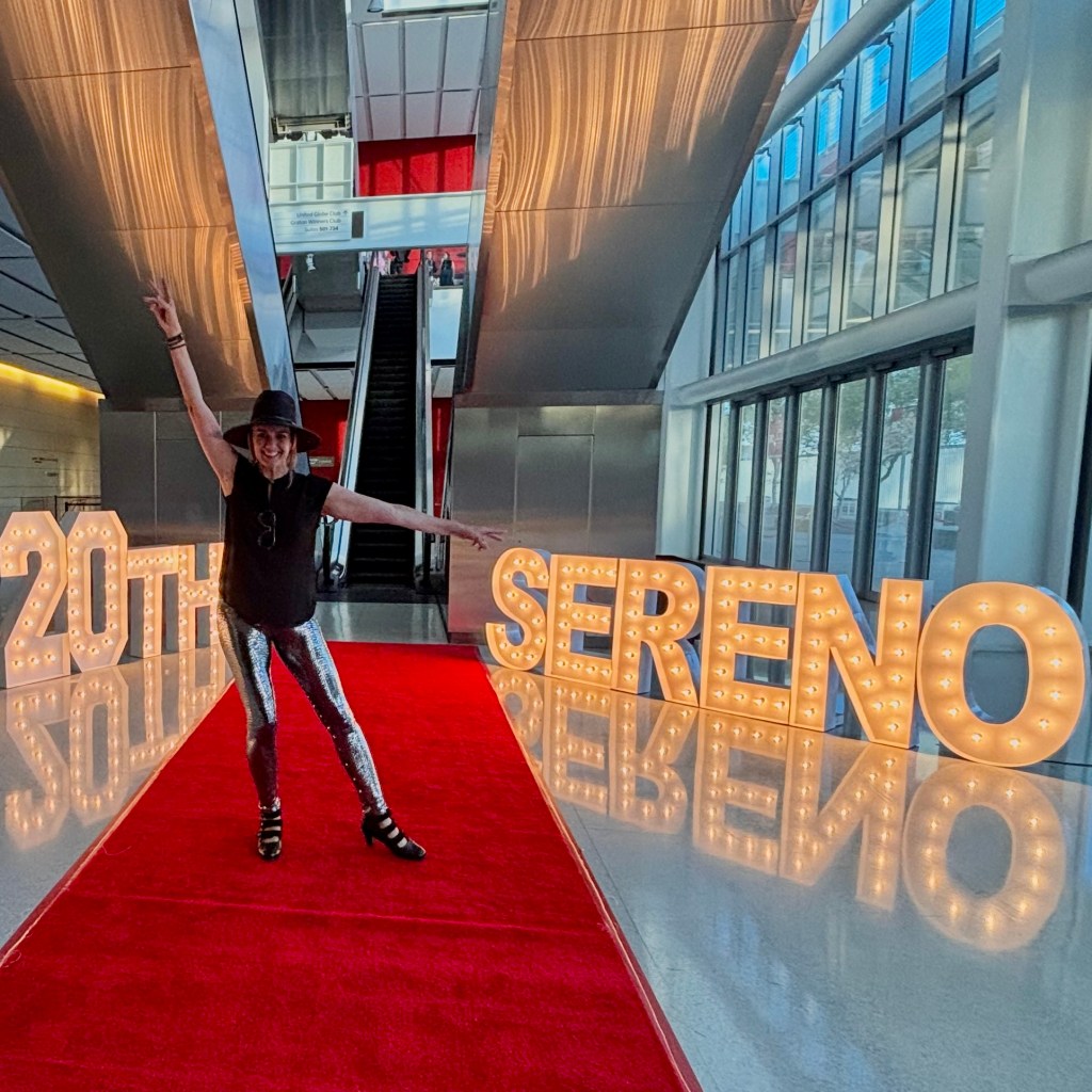 Jeny Smith at Sereno's 20th anniversary celebration, standing beside illuminated 20th and Sereno marquee letters