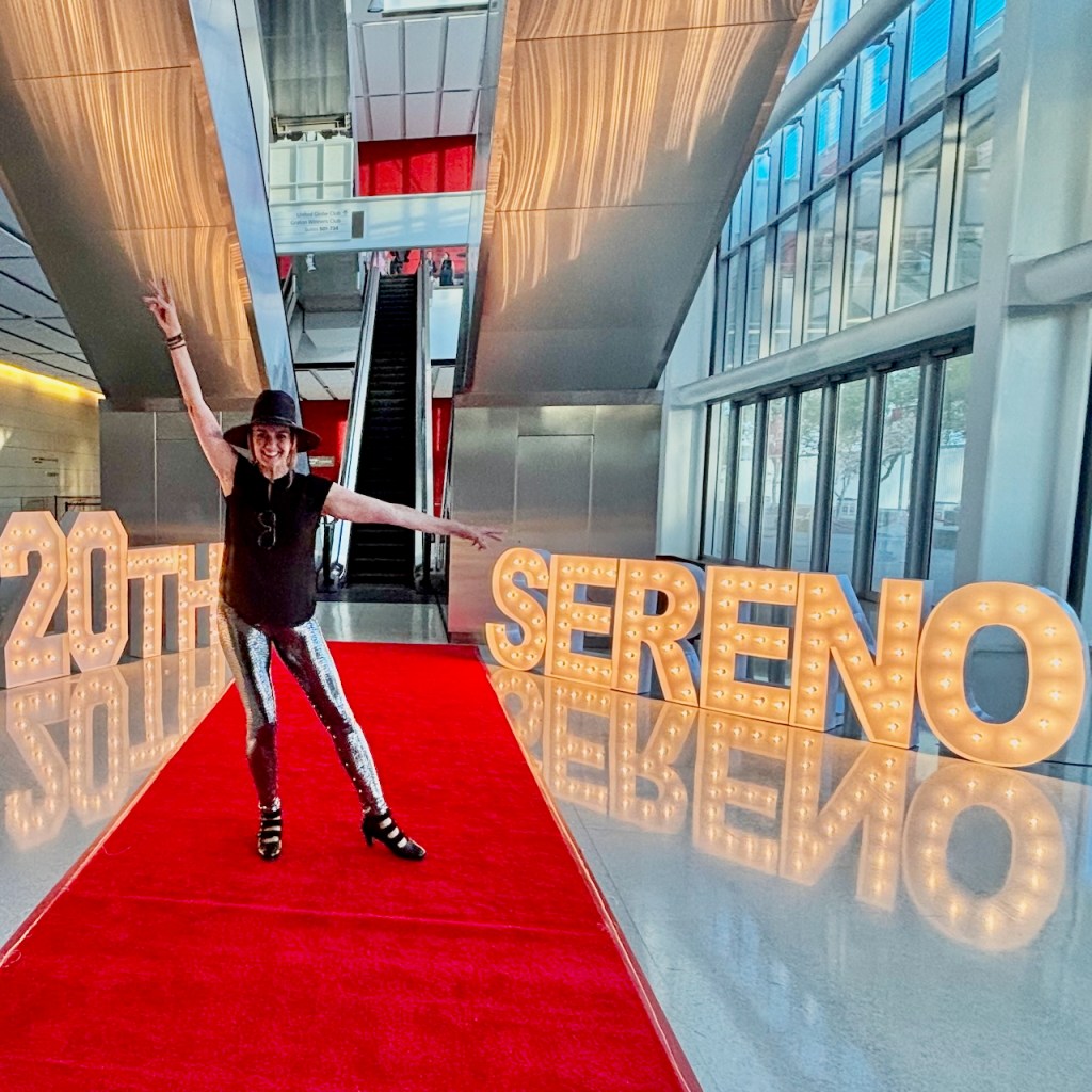 Jeny Smith at Sereno's 20th anniversary celebration, standing beside illuminated 20th and Sereno marquee letters
